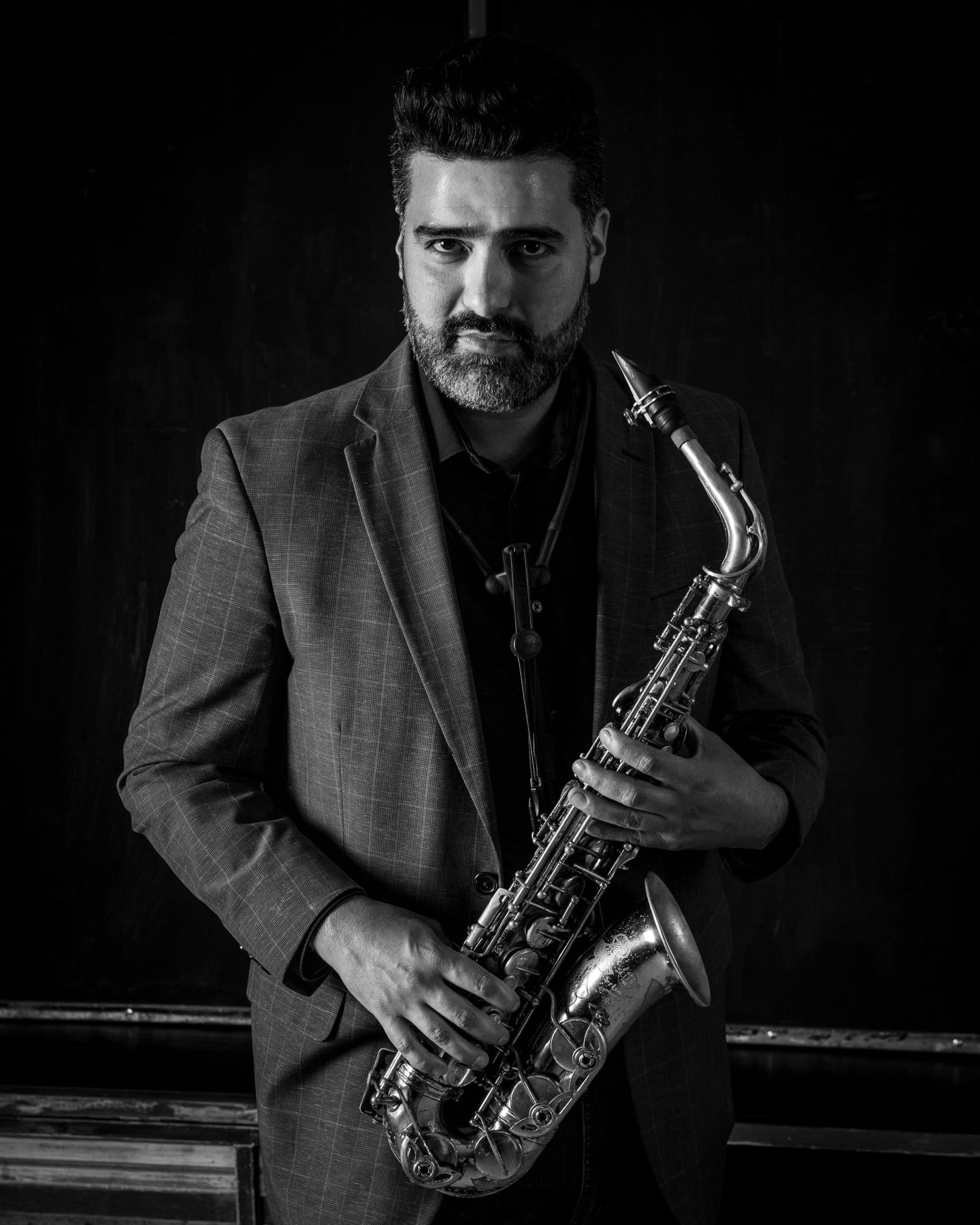 Mario Montes Lara professional headshot Mario Montes Lara, dressed in a suit, holds an alto saxophone in his professional headshot