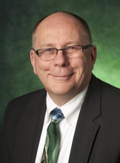 Bob Brown posing in front of green background. 