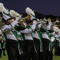 Several trumpet players in full uniform perform at halftime