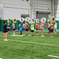 A sousaphone section leader leads an exercise in the indoor practice facility