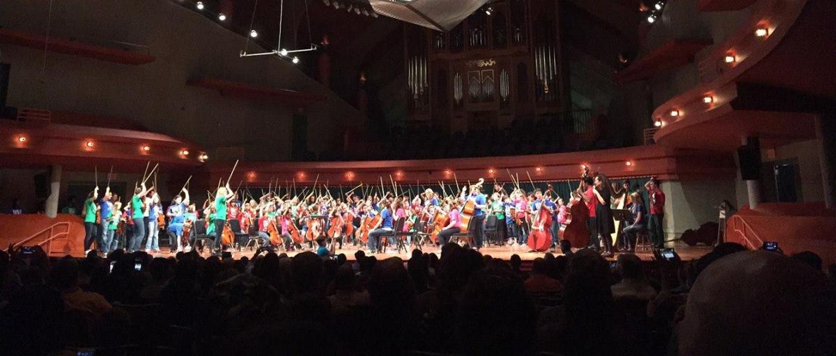 A photo with a large group of string students on stage