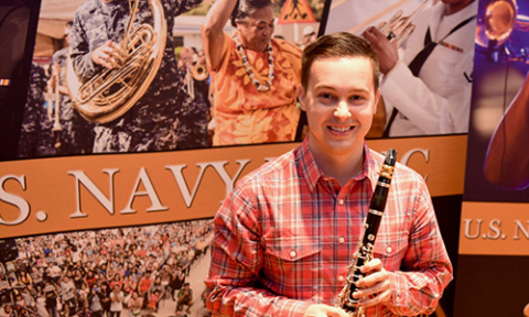 Brandon Pace with Clarinet in front of Army publicity materials