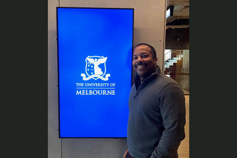 Nick Williams posing in front of University of Melbourne sign